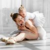 Young mother hugging little smiling daughter in ballet studio