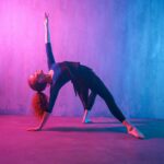 Modern dance girl dancer dancing in neon light doing gymnastic exercises in studio, copy space.