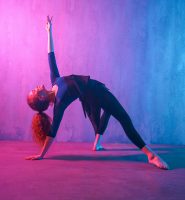 Modern dance girl dancer dancing in neon light doing gymnastic exercises in studio, copy space.